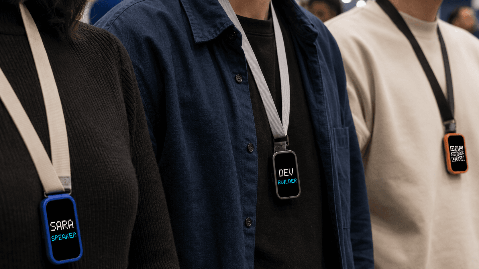 Three conference lanyards, each carrying a MoodPin showing a name and role in pixel type